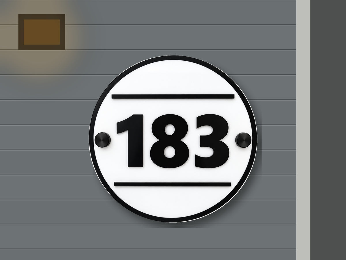 Round modern black and white address sign 183 shown installed on a contemporary home exterior